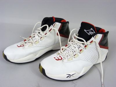 une paire de baskets blanches et rouges avec des semelles noires sur un fond blanc