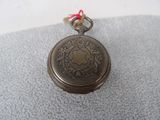 a small silver pocket watch with a red string around it