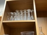 des bouteilles et des verres posés sur une étagère dans une cuisine aux étagères en bois