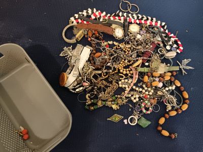 a tray of jewelry on the floor next to a container of beads