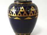 a blue and gold vase on a white surface