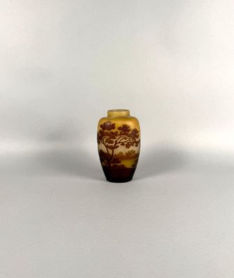 a small vase with a tree on it sitting on a white surface