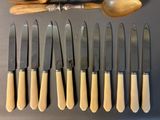 six knives and a spoon are lined up on a table