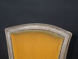 a close up of a yellow chair against a black wall