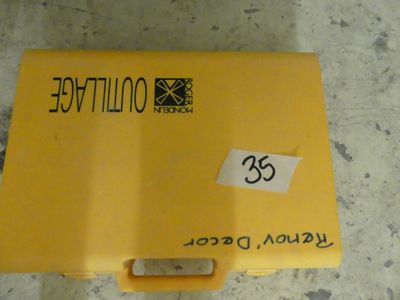une boîte jaune posée par terre, sur laquelle est collé un autocollant