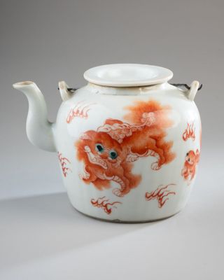 a white tea pot with a red design on it