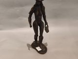 statue d'un homme coiffé d'un chapeau, debout sur un skateboard posé sur une surface blanche