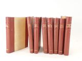 six livres rouges sont alignés sur une surface blanche