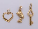 three gold charms with a heart, key, and an egyptian head