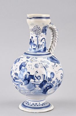 blue and white vase with a handle on a stand on a gray surface