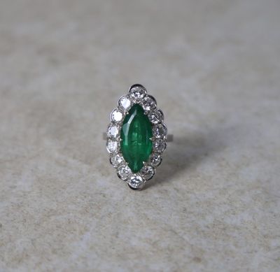 un gros plan d'une bague sertie d'une émeraude et de diamants posée sur une table