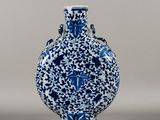 a blue and white vase sitting on a gray surface