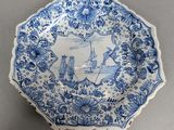 an old blue and white plate with a picture of a man and woman in a boat