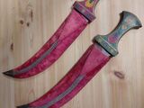 two knives are laying on a wooden surface next to each other