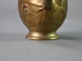 a gold vase with a flower on it sitting on a table