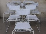 several white metal chairs are stacked on top of each other in front of a wall