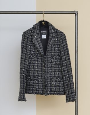 une veste en tweed noir et blanc suspendue à un portant