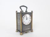 une petite horloge posée sur une surface blanche