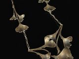 a close up of a silver necklace with leaves on it