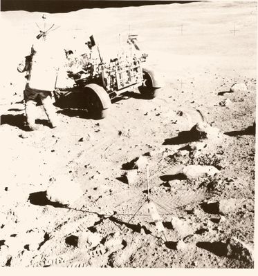 photographie en noir et blanc d'un homme sur la Lune avec un chariot rempli d'objets
