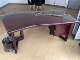 a wooden desk with a glass top in a room
