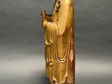 statue of a man in a golden robe holding a flower
