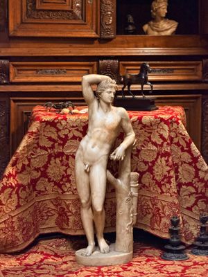 une statue représentant un homme assis sur une table recouverte d'une nappe rouge