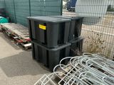 a pile of black trash cans sitting next to a fence