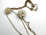 a close up of a necklace with pearls on a chain