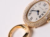 a gold watch with diamonds on it on a white surface