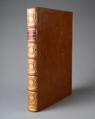 un livre marron aux bords dorés et à la reliure rouge
