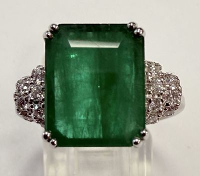 gros plan d'une bague avec une pierre verte entourée de diamants blancs
