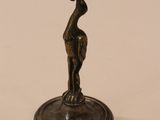 statue en bronze représentant un oiseau sur un socle, sur fond blanc