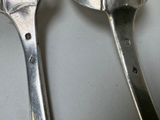 two spoons that are sitting next to each other on a table