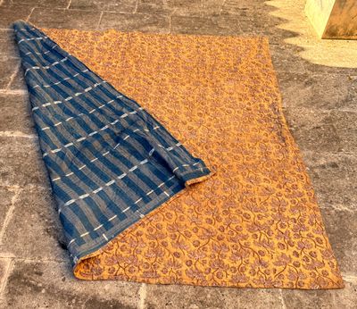 un gros plan sur une couverture bleue et orange posée sur un sol en pierre