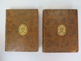 pair of antique leather bound books with gold emblems