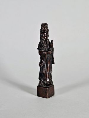 une vieille statue en bois représentant un homme portant un chapeau et une robe