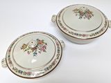 two white dishes with floral designs on them on a table