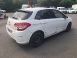 the back of a white car is parked in a parking lot