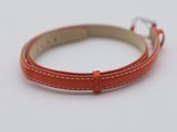 a close up of a red leather bracelet on a white surface