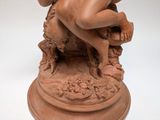 a statue of a naked man sitting on a pedestal