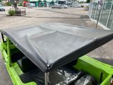 a green jeep with a black cover in the back of it