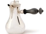 a silver coffee pot with a black handle on a white background