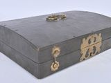 une petite boîte en bois munie d'une poignée métallique, posée sur une surface blanche