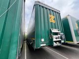 two green semi trucks that are parked on the side of the road