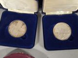 two silver coins in a blue case on a table