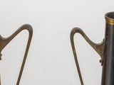 pair of metal and wood vases with handles on a white surface