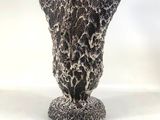 a black and white vase sitting on a white surface