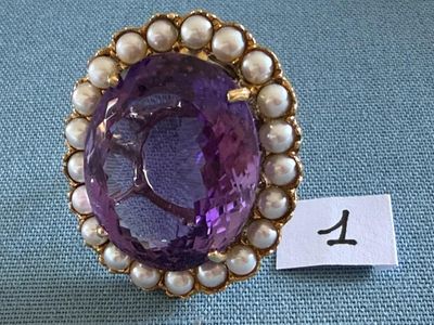 une image représentant une bague violette et blanche ornée de perles, sur fond bleu
