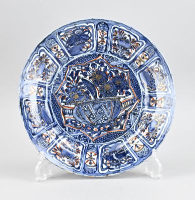 une image représentant une assiette bleue et blanche ornée d'un blason